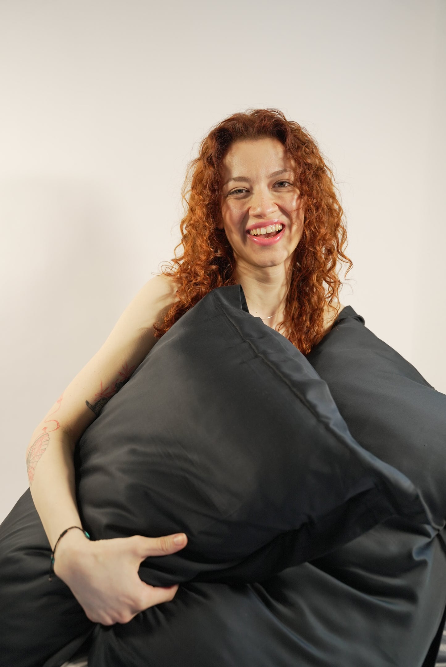 Model holding BetterBe bamboo pillowcase against body, silky soft feel that reduces friction