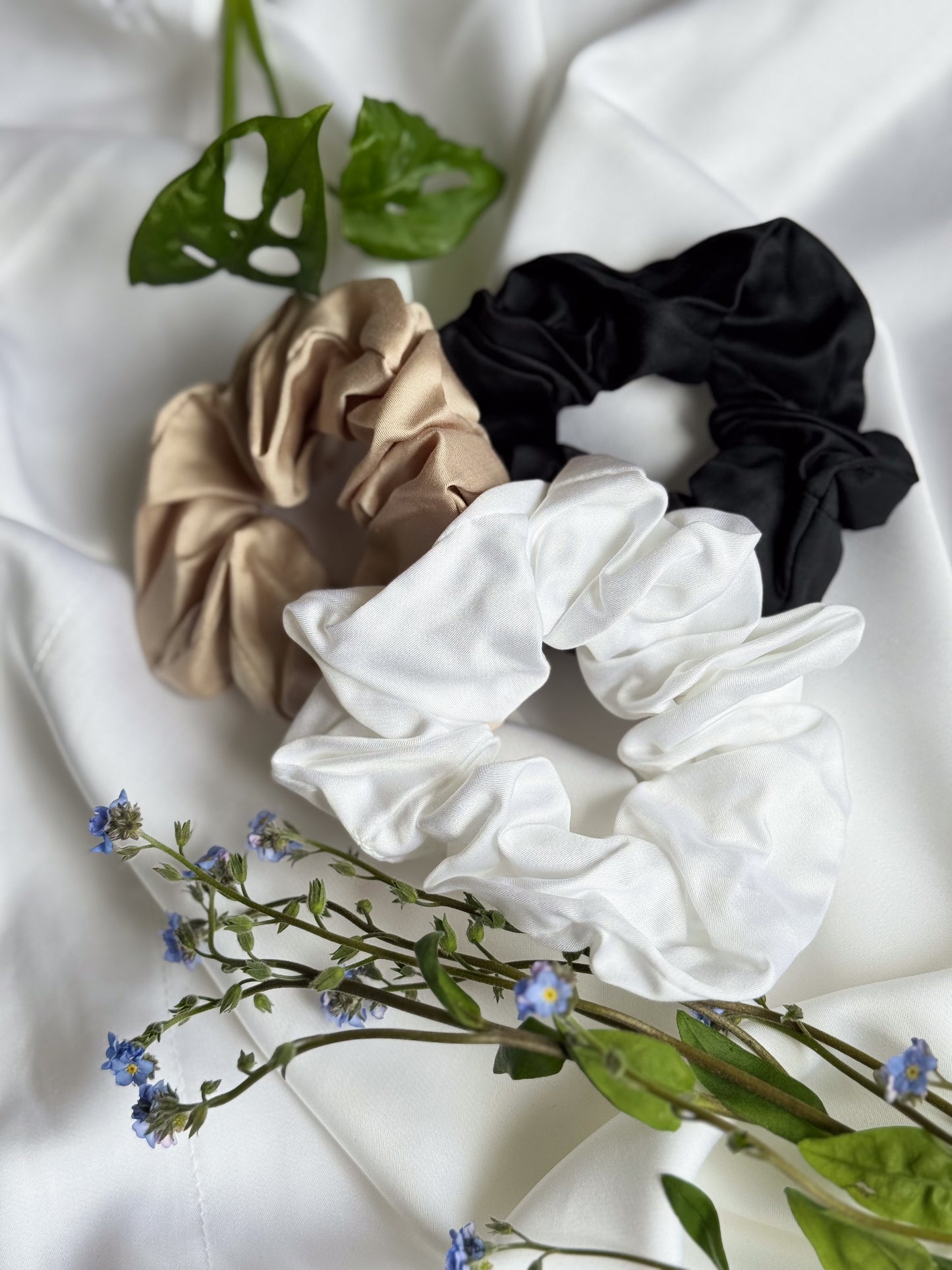 BetterBe bamboo scrunchies flat lay in Raven Black, Pearl White, and Bubbly Champagne