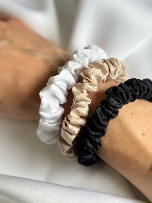 Hand holding BetterBe bamboo scrunchies set, Raven Black Pearl White Bubbly Champagne