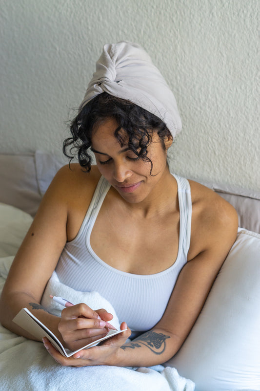 BetterBe bamboo sleep bonnet on model at night, breathable fit that protects curls from frizz