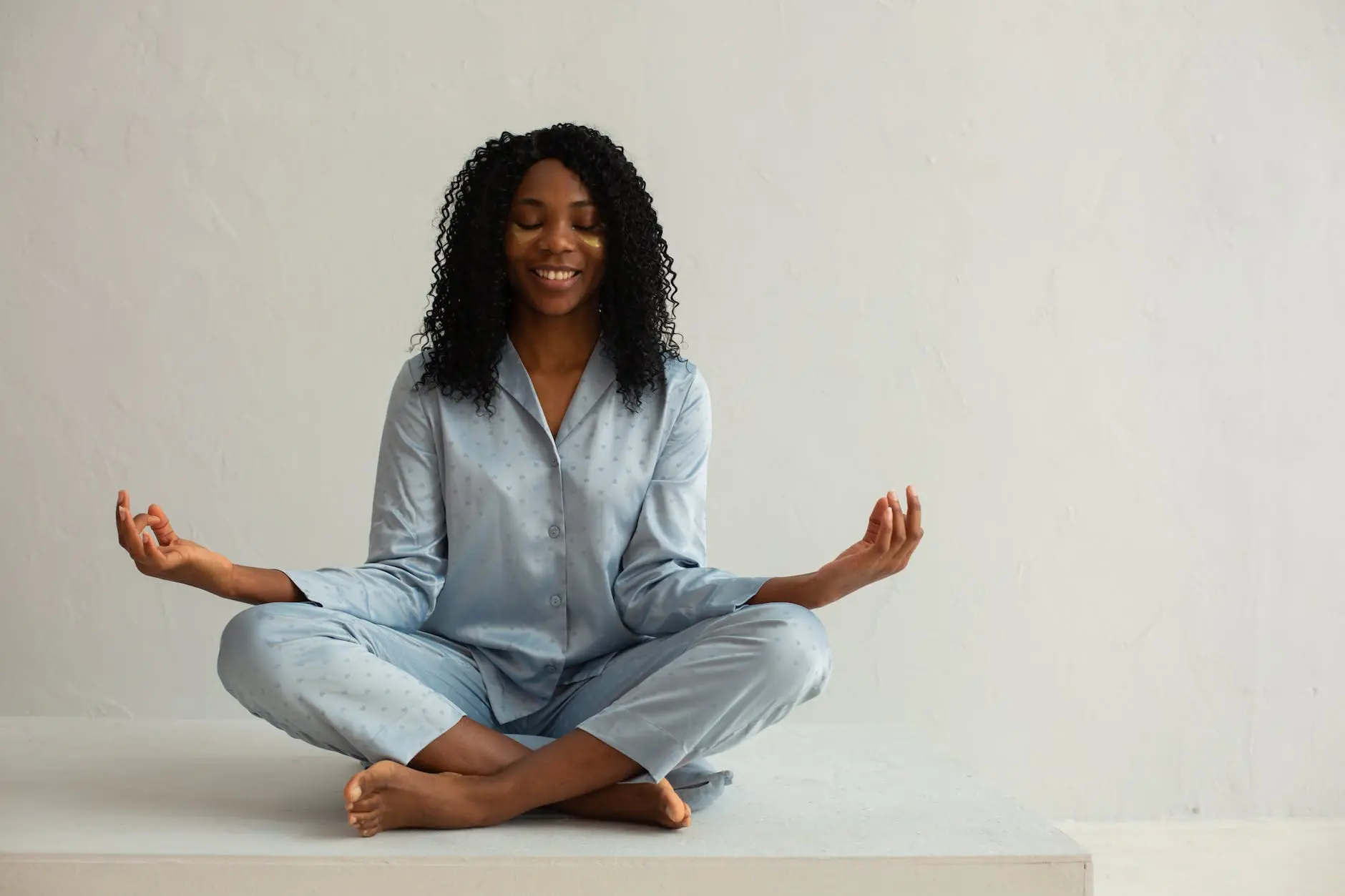 Meditating coloured woman in pyjama with curls