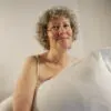 Woman with short blonde curls holding a pillow