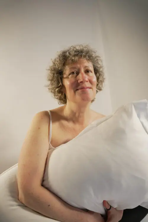 Woman with short blonde curls holding a pillow